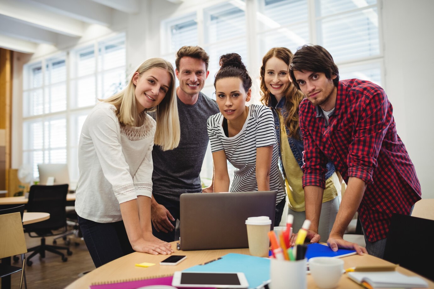 group-business-executives-smiling-camera-their-desk_1170-2009